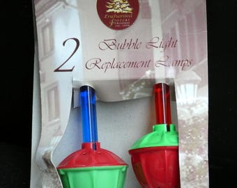 May include: Two bubble light replacement lamps in a package. The lamps have a red top, green base, and a blue or red tube. The package has the text "Enchanted Forest Christmas" and "Bubble Light Replacement Lamps".