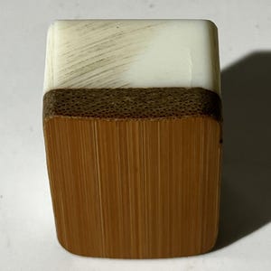 Puede incluir: Una ficha de mahjong rectangular que presenta una secci&oacute;n superior blanca lisa con sutiles estr&iacute;as diagonales y una secci&oacute;n inferior m&aacute;s grande de bamb&uacute; marr&oacute;n claro con veta vertical visible y una banda horizontal texturizada.