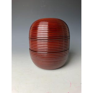 May include: A set of three red lacquered nesting boxes with a ribbed design. The boxes are stacked on top of each other.