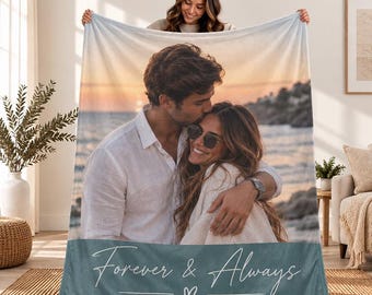 May include: A rectangular throw blanket featuring a photographic print of a couple embracing on a beach at sunset. The bottom section is a solid muted blue color with the white cursive text Forever & Always and a small heart symbol centered below.