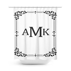 May include: White shower curtain with a black ornate frame and the monogram "AMK" in the center.
