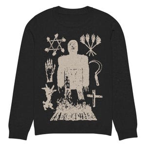 May include: A black long-sleeve shirt with a white graphic print of a stick figure surrounded by symbols, including a star, a cross, a whip, and a goat.
