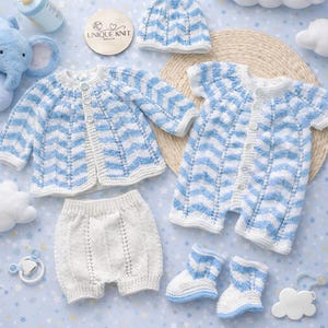 May include: A baby knitwear set in white and light blue chevron patterns. The set includes a cardigan, romper, shorts, hat, and booties. A dummy, bottle, and plush elephant are also present.