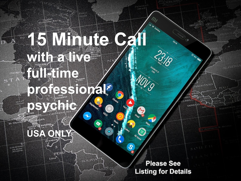 Puede incluir: Un tel&eacute;fono inteligente negro con un fondo de mapa del mundo y el texto "15 Minute Call with a live full-time professional psychic USA ONLY" en la pantalla. La pantalla del tel&eacute;fono muestra la hora 23:18 y la fecha 9 de noviembre. El texto "Please See Listing for Details" est&aacute; en la parte inferior de la imagen.