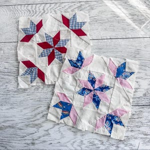 May include: Two vintage quilt blocks with star patterns. One block features red and blue plaid stars, the other has pink and blue floral stars. Both are on a white background, showcasing the patchwork design.