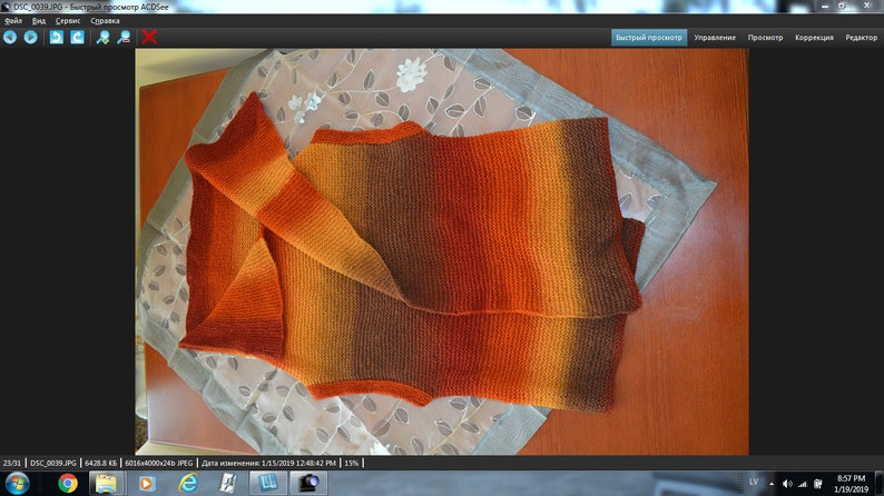 Peut inclure: Un gilet sans manches en tricot avec un d&eacute;grad&eacute; de couleurs orange, marron et jaune. Le gilet est pli&eacute; en deux et pos&eacute; &agrave; plat sur une table.