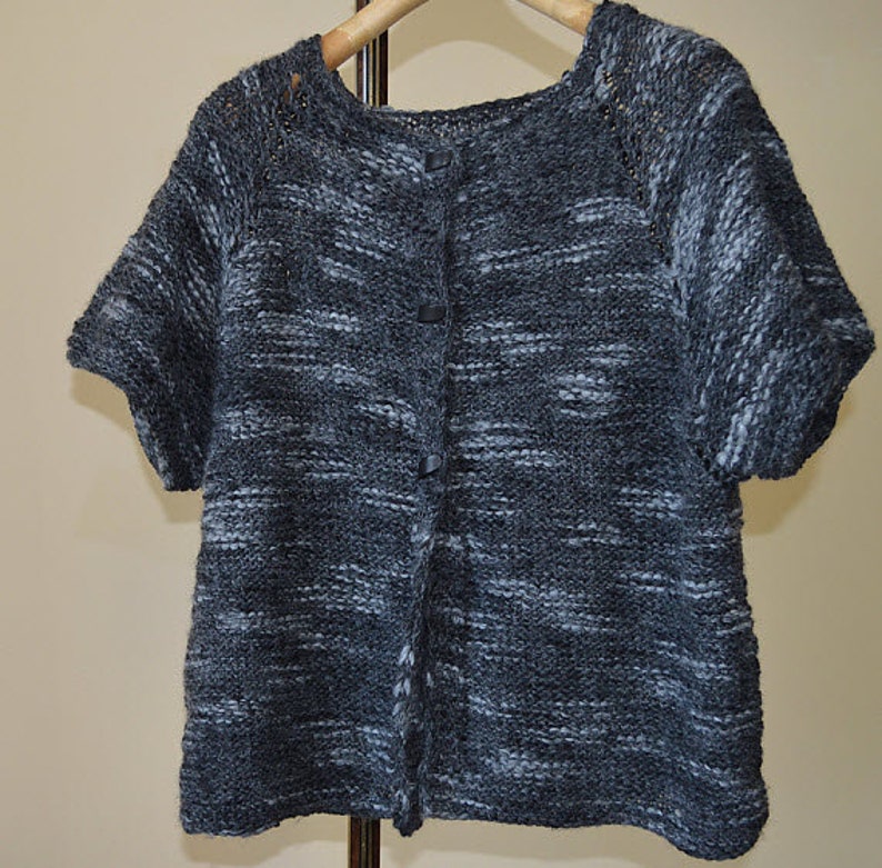 May include: A grey and white knitted cardigan with short sleeves and a button fastening.