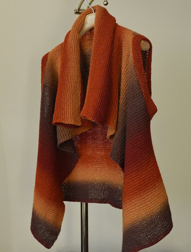 Peut inclure: Un cardigan en tricot sans manches avec un d&eacute;grad&eacute; de couleurs orange, marron et bordeaux. Le cardigan a un col drap&eacute; et une coupe ample.