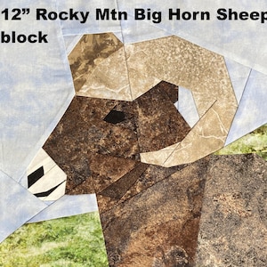 May include: A 12-inch Rocky Mountain Big Horn Sheep block. The block features a geometric design of a sheep's head and horns, with brown, tan, and white fabric pieces. The background is light blue and green.