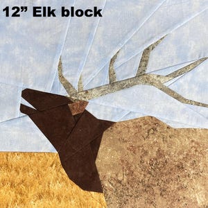 Può includere: Un quadrato di trapuntatura Elk da 12 pollici (30 cm). L'alce è raffigurato in tonalità marroni e beige, con un aspetto strutturato. Le corna sono di colore grigio chiaro. Lo sfondo presenta un cielo azzurro chiaro e un ciuffo d'erba beige.