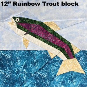 May include: A 12-inch Rainbow Trout block, featuring a colorful fish leaping from blue water. The fish has a purple and green body, with beige fins and a white belly. The background is light blue with white accents.