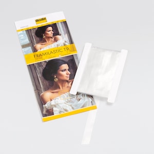 Könnte beinhalten: Eine weiße Verpackung mit einem gelben Etikett, auf dem "FRAMILASTIC T9" steht und ein Bild einer Frau. Die Verpackung liegt neben einer Rolle weißen Gummibands.