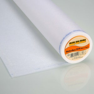 Könnte beinhalten: Eine Rolle weißer Stickvlies/314 Stitch-n-Tear-Vlieseline. Das Etikett ist orange mit schwarzem Text und einem Barcode. Das Etikett lautet "Stickvlies/314 Stitch-n-Tear" und "70% CV 30% Holzstoff".
