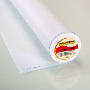 Könnte beinhalten: Eine weiße Rolle Vieseline Vilene Fliselina F 220/304 Einlage für Nähprojekte. Das Etikett ist gelb mit rotem Text und einem Barcode. Die Rolle ist 90 cm x 2,5 m groß und besteht aus 50 % PES und 50 % CV.