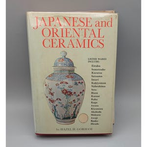 May include: A book titled "JAPANESE and ORIENTAL CERAMICS" with a detailed illustration of a ceramic vase. The cover features a list of ceramic ware types, including Eiraku, Sometsuke, and Karatsu. The author's name, HAZEL H. GORHAM, is at the bottom.