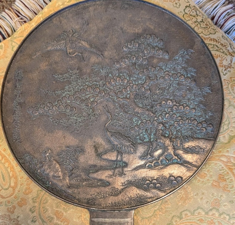 Antique Japanese Kagami - Bronze Antique Hand Mirror - Flying Cranes Turtle, Pine Trees, Pond Theme Meiji or Taishō Period 1868-1926
This piece roughly from the Meiji period (1868-1921) or Taisho period (1921-1926) is a Japanese bronze