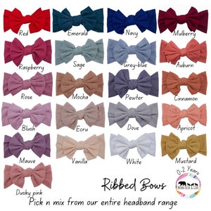 May include: A collection of 18 ribbed fabric headbands in various colours, including red, emerald, navy, mulberry, raspberry, sage, grey-blue, auburn, rose, mocha, pewter, cinnamon, blush, ecru, dove, apricot, mauve, vanilla, white, and mustard. The headbands are arranged in rows of three, with the text "Ribbed Bows" and "Pick n mix from our entire headband range" below the image. The text "0-2 Years" is also visible in the image.