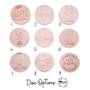 May include: Nine wooden discs with various engraved designs for baby milestones. The designs include "hello I'm new here", "It's a girl", "hello little one", "hello world", "It's a boy", "hello little one", "SHHH... baby sleeping", "My first tooth", and "My 1st birthday".