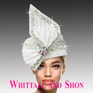 May include: A white head covering with a decorative bow and sparkling embellishments. The headpiece is adorned with iridescent rhinestones and a central jewel. The text "WHITTALL AND SHON" is displayed in pink.