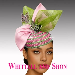 May include: A pink and green embellished hat with butterfly accents. The hat features a pink satin bow, green mesh accents, and a beaded crown. The text "WHITTALL AND SHON" is displayed in pink at the bottom of the image.
