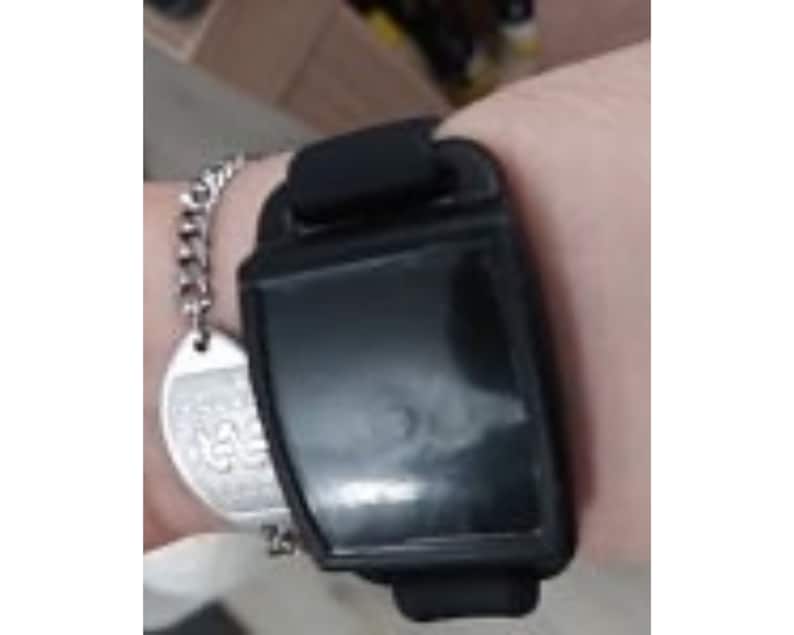 Close up view of a black nvs magnet with a black silicone band on an adult wrist.