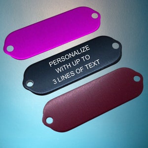 May include: Three metal keychains in different colours: purple, black and burgundy. The black keychain has the text "PERSONALIZE WITH UP TO 3 LINES OF TEXT" engraved on it.