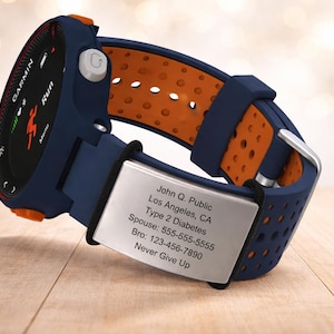 May include: A navy blue and orange Garmin smartwatch with a silver metal plate. The watch displays the word "Run" and a running figure on the screen. The plate has contact information and the text "Never Give Up".
