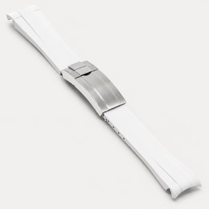 Puede incluir: Una correa de reloj blanca con un cierre de acero inoxidable. La correa est&aacute; hecha de un material flexible y tiene un dise&ntilde;o curvo. El cierre tiene un acabado de metal cepillado.