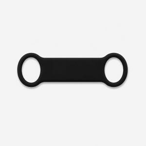May include: A black silicone tag with a rectangular central section and circular loops at each end. The tag is designed for attachment to a pet collar or similar item. The tag is made of a flexible material.