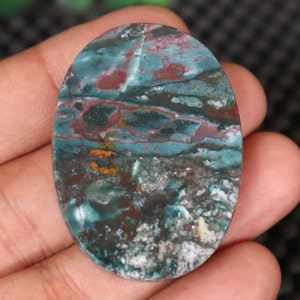 Pode incluir: Caboch&atilde;o oval de &aacute;gata verde, marrom e branco com um padr&atilde;o de redemoinho.