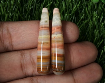 May include: Pair of long, pointed, multi-coloured agate cabochons with a banded pattern in shades of brown, orange, pink, and white.
