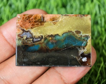 May include: A colorful agate cabochon with a mix of orange, yellow, blue, and black colors. The stone has a layered pattern and a smooth, polished surface.