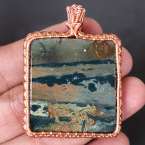 May include: A square copper wire wrapped pendant featuring a green, brown, and white agate stone with a swirling pattern.