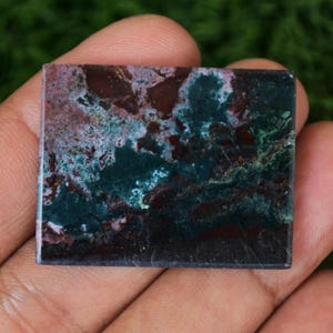 May include: A rectangular green, red and white agate cabochon with a polished surface.