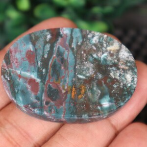 Pode incluir: Uma pedra oval polida com um padr&atilde;o de redemoinho em tons de verde, vermelho e branco.