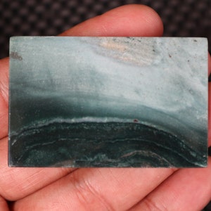 May include: A smooth, polished green and white stone with a banded pattern. The stone has a natural, organic look and is a great example of the beauty of nature.