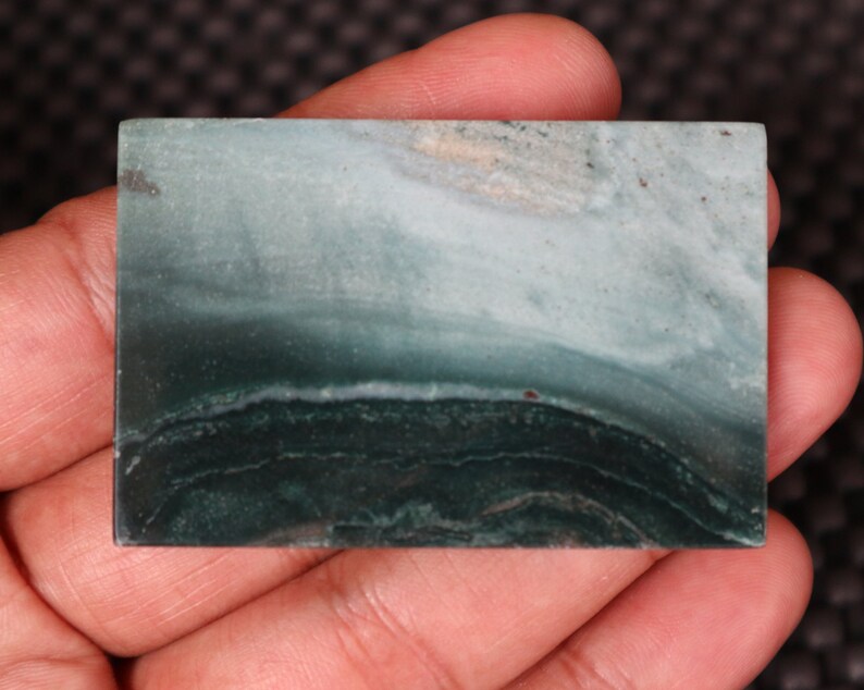 May include: A smooth, polished green and white stone with a banded pattern. The stone has a natural, organic look and is a great example of the beauty of nature.