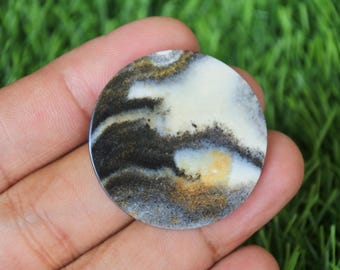 Könnte beinhalten: Ein runder, weißer, schwarzer und goldener Achat-Cabochon mit einem wirbelnden Muster. Der Cabochon hat einen Durchmesser von etwa 5 cm.