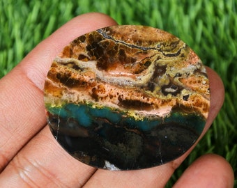 May include: A round, polished, multi-colored agate cabochon with a layered pattern of brown, orange, green, and black. The stone has a natural, organic look.