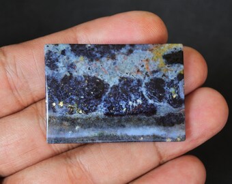 May include: A rectangular slab of blue, white, and black agate with gold flecks. The agate has a swirling pattern and a smooth, polished surface.