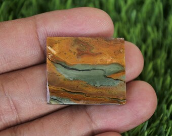 May include: A square-shaped, polished stone with a layered pattern of brown, orange, and green colours. The stone has a smooth, polished surface.