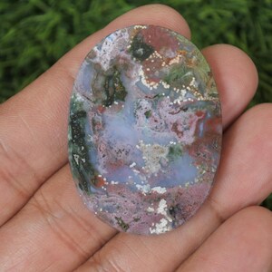 May include: A polished oval cabochon of green, pink, and white agate with a swirling pattern. The stone has a high polish and is translucent.