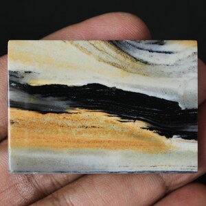 May include: A rectangular slab of banded agate with black, white, and yellow stripes. The agate has a polished surface and is a natural stone.