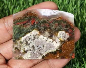 Op de afbeelding: Een gepolijste agaatplaat met een uniek patroon van groen, rood, wit en bruin. De agaat heeft een natuurlijke, organische uitstraling.