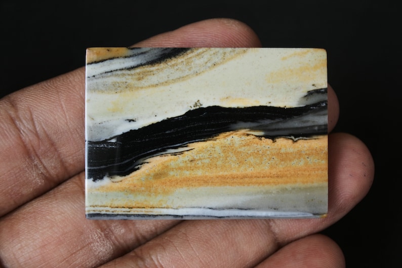 May include: A rectangular slab of polished stone with a layered pattern of black, white, and brown. The stone has a natural, organic look.