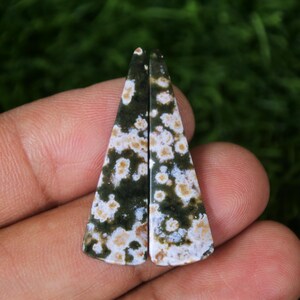 Puede incluir: Dos cabujones de piedra preciosa triangulares de color verde, blanco y marrón. Los cabujones miden aproximadamente 2,5 cm de largo.