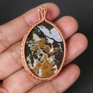 May include: A copper wire wrapped pendant featuring a colourful agate stone with brown, white and yellow patterns.