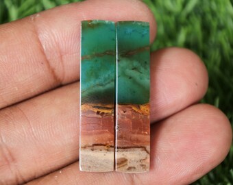 May include: Two rectangular green, brown and white gemstone cabochons. The cabochons are approximately 5 cm long and 1.25 cm wide.