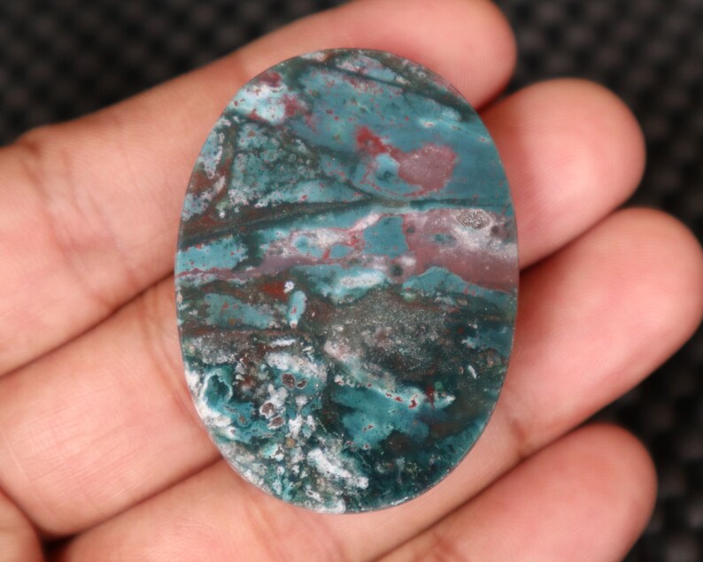 Pode incluir: Caboch&atilde;o oval de &aacute;gata verde, azul e marrom com um padr&atilde;o de redemoinho.