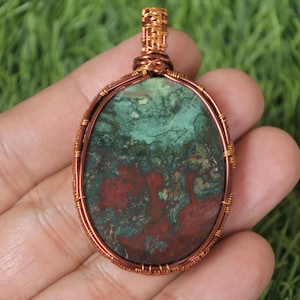 May include: A copper wire wrapped pendant featuring a green and red agate stone with a swirling pattern.